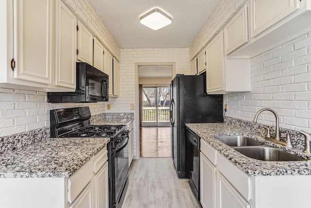 kitchen featuring black appliances, a sink, backsplash, and light wood finished floors