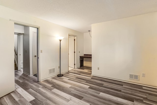 unfurnished room with wood finished floors, stairs, and a textured ceiling