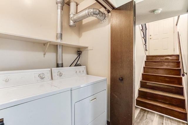 clothes washing area featuring washer and clothes dryer and light wood-style floors
