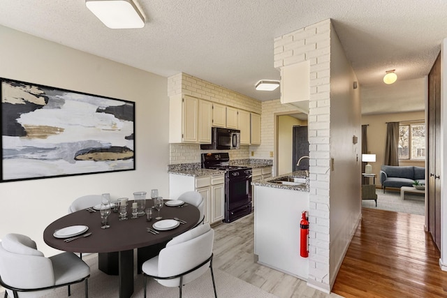12186 Drake St NW, Coon Rapids, MN 55448 - kitchen featuring black appliances, a sink, light wood finished floors, decorative backsplash, and light stone counters