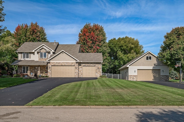 craftsman-style house with fence, a front lawn, driveway, and stone siding