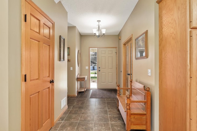 foyer featuring visible vents, a notable chandelier, and baseboards