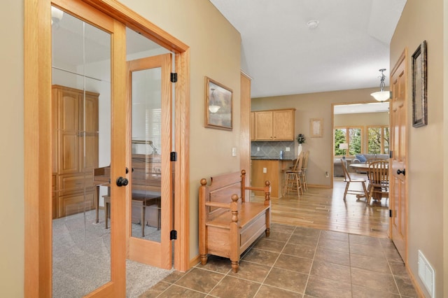 hallway featuring visible vents, dark tile patterned floors, and baseboards