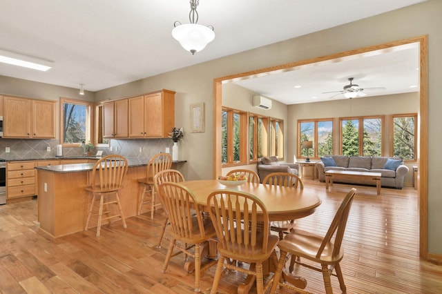 dining space featuring ceiling fan, a wealth of natural light, light wood finished floors, and a wall mounted AC