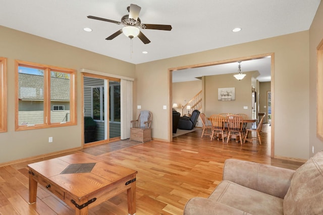 living area with baseboards, light wood-type flooring, recessed lighting, a ceiling fan, and stairs