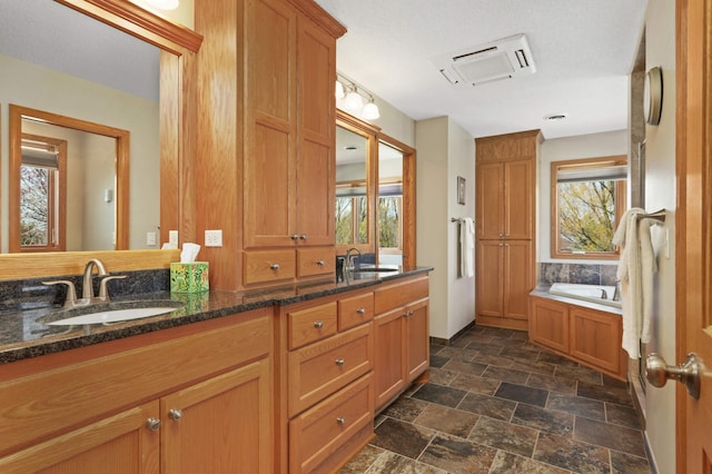 full bathroom with plenty of natural light, stone finish floor, and a sink
