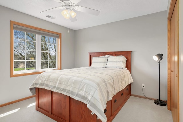 bedroom with baseboards, visible vents, and light carpet