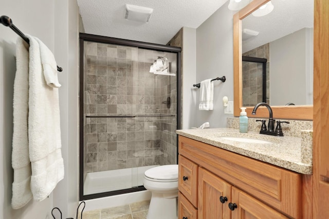 full bath featuring toilet, a stall shower, a textured ceiling, and vanity