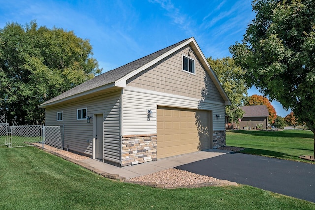 view of property exterior with stone siding, an outbuilding, fence, a yard, and a garage