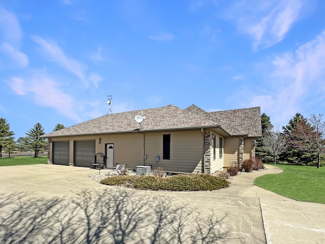 view of home's exterior featuring central AC unit, an attached garage, driveway, a lawn, and roof with shingles