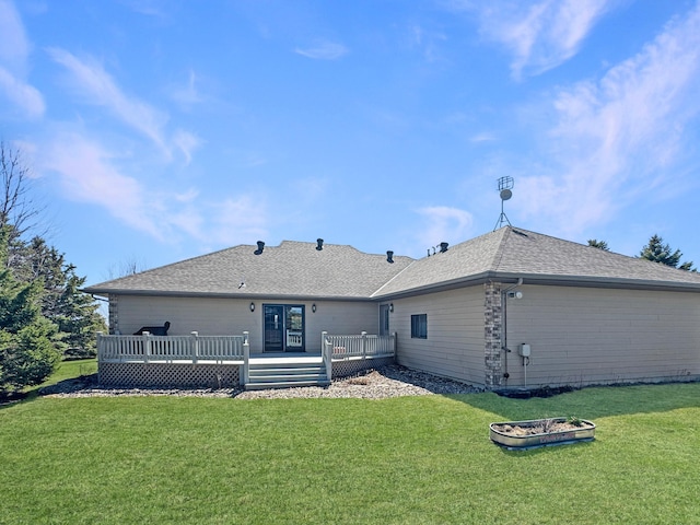 rear view of property featuring a lawn, a wooden deck, and a shingled roof