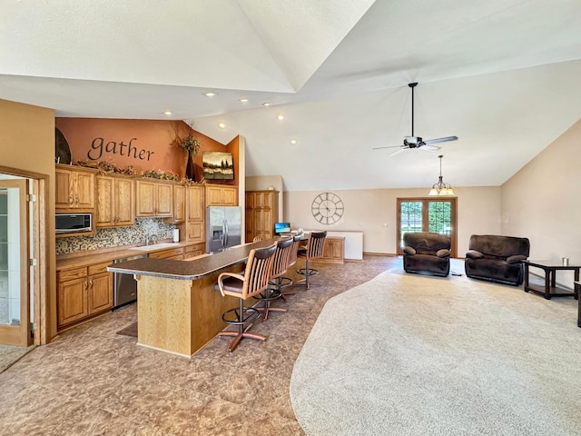 kitchen featuring a center island, open floor plan, appliances with stainless steel finishes, ceiling fan, and a breakfast bar area