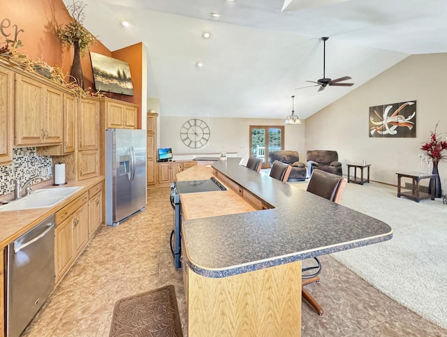 kitchen featuring a ceiling fan, a kitchen breakfast bar, a sink, an island with sink, and appliances with stainless steel finishes
