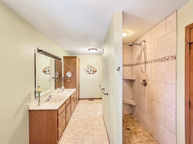 bathroom with a sink, double vanity, and tiled shower