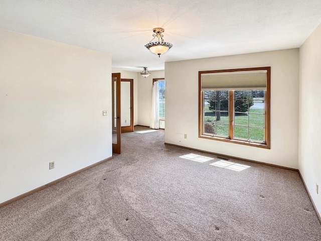 carpeted empty room featuring baseboards