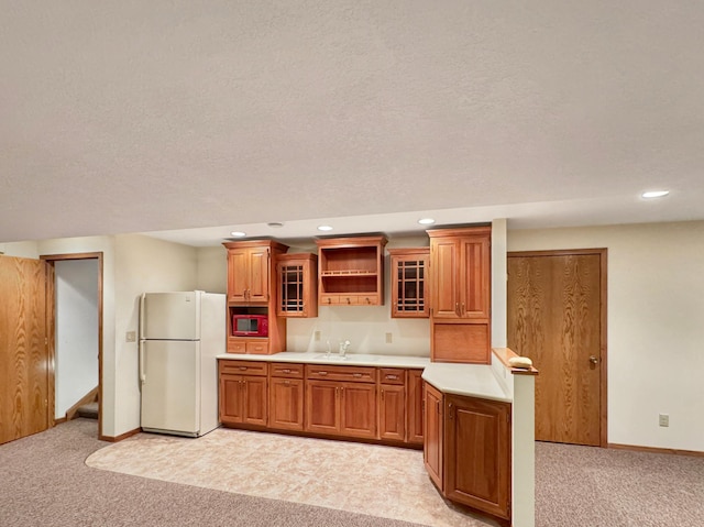 kitchen with light carpet, freestanding refrigerator, and brown cabinets