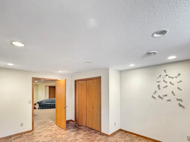 basement with baseboards, a textured ceiling, visible vents, and recessed lighting