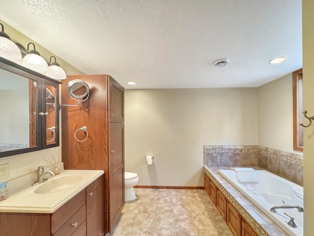 bathroom with a whirlpool tub, toilet, vanity, baseboards, and a textured ceiling