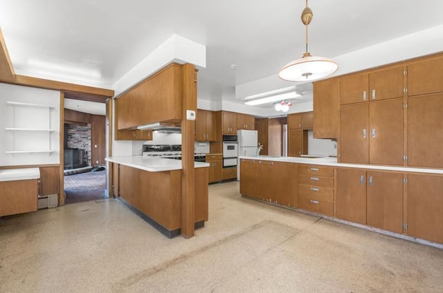 kitchen with brown cabinets, light countertops, white appliances, and a peninsula