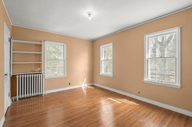 empty room featuring a wealth of natural light, radiator, and baseboards