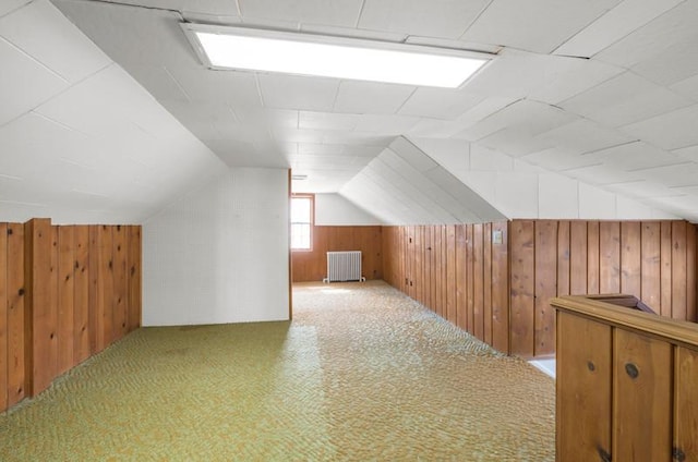 bonus room featuring radiator, wooden walls, vaulted ceiling, and carpet