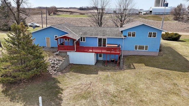 rear view of house featuring a yard, a shingled roof, and a deck