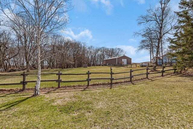 view of yard with fence, a rural view, an outdoor structure, and a pole building