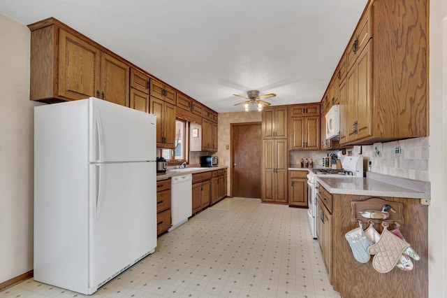 kitchen with light floors, light countertops, white appliances, brown cabinetry, and ceiling fan
