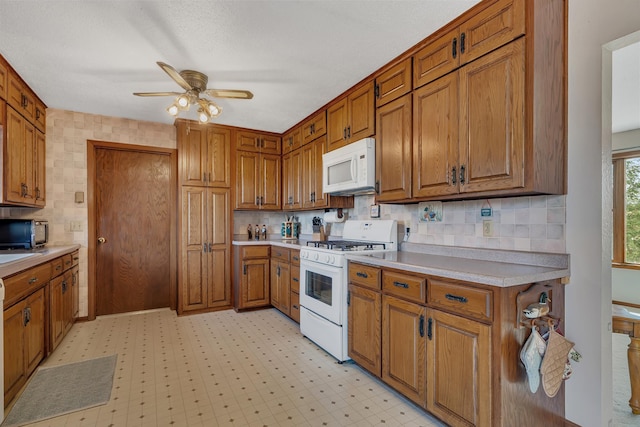 kitchen with brown cabinets, light countertops, a ceiling fan, and white appliances