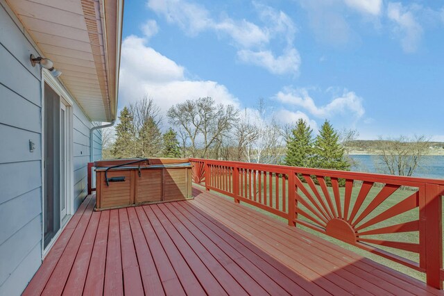 wooden deck featuring a hot tub and a water view