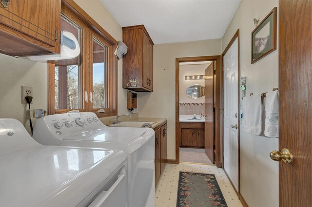 laundry area with cabinet space, washer and dryer, light floors, and a sink