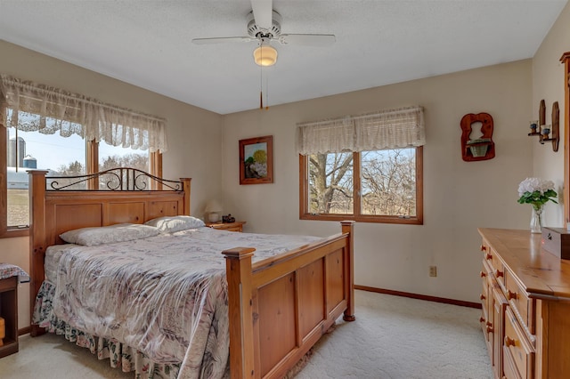 bedroom with ceiling fan, light carpet, multiple windows, and baseboards