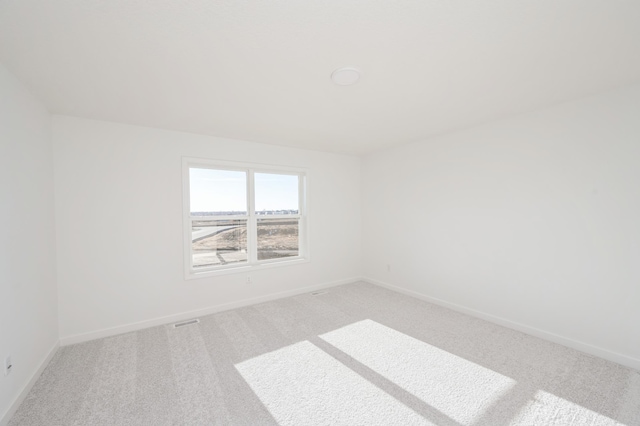 unfurnished room featuring baseboards, visible vents, and light colored carpet