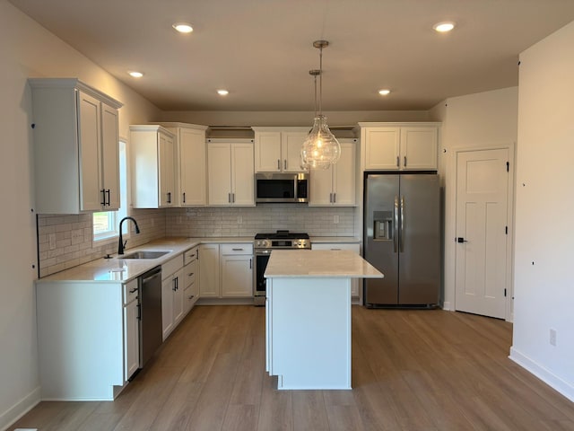 kitchen featuring wood finished floors, a sink, light countertops, appliances with stainless steel finishes, and a kitchen island