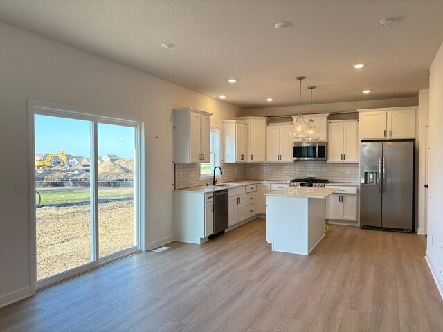 kitchen with backsplash, light wood-style floors, stainless steel appliances, and light countertops