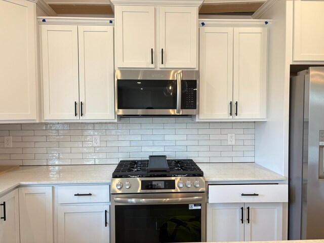 kitchen with appliances with stainless steel finishes, tasteful backsplash, white cabinetry, and light stone countertops