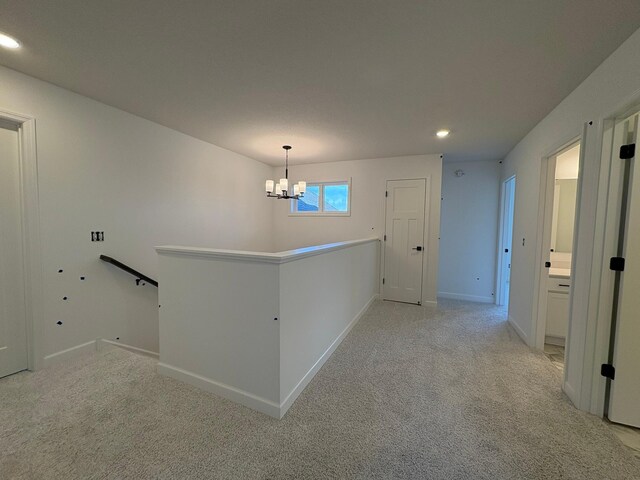 hallway with recessed lighting, an upstairs landing, baseboards, light colored carpet, and a notable chandelier