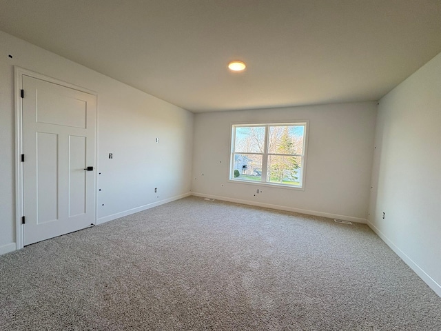 carpeted empty room with visible vents and baseboards