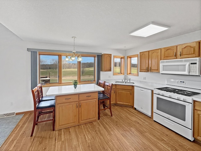 kitchen featuring light wood finished floors, a sink, a notable chandelier, white appliances, and light countertops