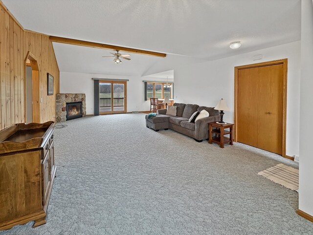 living room featuring a ceiling fan, lofted ceiling with beams, wooden walls, a fireplace, and carpet flooring