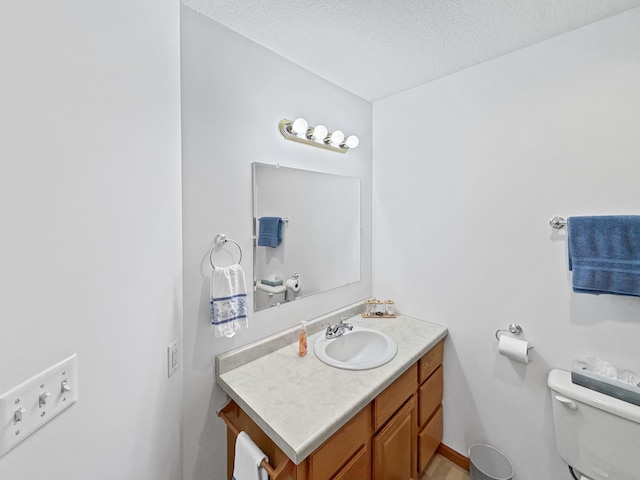 half bath featuring vanity, a textured ceiling, and toilet