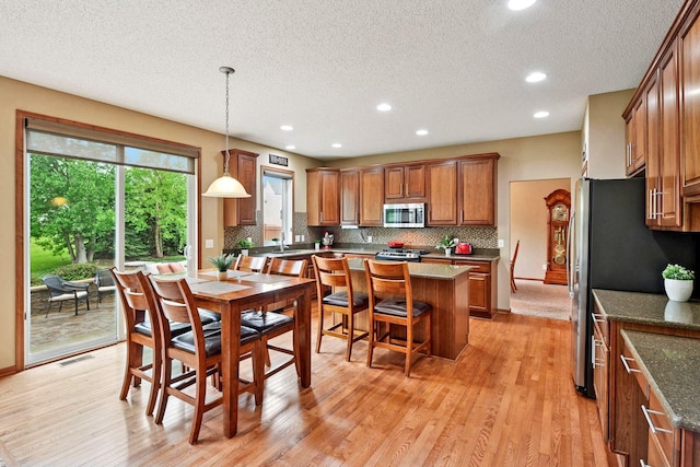 dining space featuring a textured ceiling, light wood-style floors, and recessed lighting
