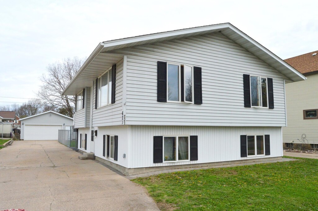 rear view of property with an outdoor structure, a yard, and a garage