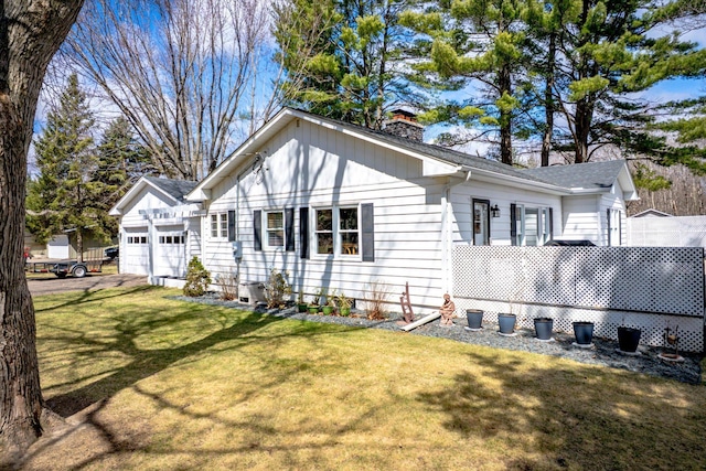 312 Walnut St, Taylors Falls, MN 55084 - view of side of property featuring a chimney, an attached garage, a lawn, roof with shingles, and asphalt driveway