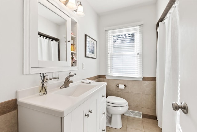312 Walnut St, Taylors Falls, MN 55084 - bathroom featuring toilet, tile patterned floors, tile walls, vanity, and wainscoting