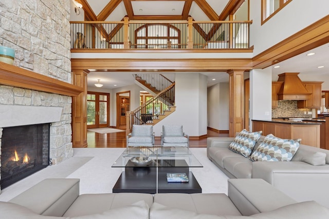 9726 Whistling Valley Rd, Lake Elmo, MN 55042 - living area featuring high vaulted ceiling, a stone fireplace, stairway, wood finished floors, and baseboards