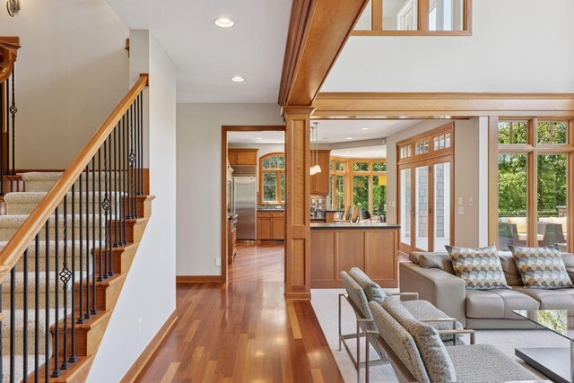 9726 Whistling Valley Rd, Lake Elmo, MN 55042 - living room with light wood-style flooring, recessed lighting, stairs, ornate columns, and baseboards