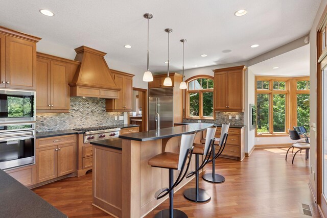9726 Whistling Valley Rd, Lake Elmo, MN 55042 - kitchen with built in appliances, custom exhaust hood, dark countertops, dark wood-style flooring, and a kitchen island