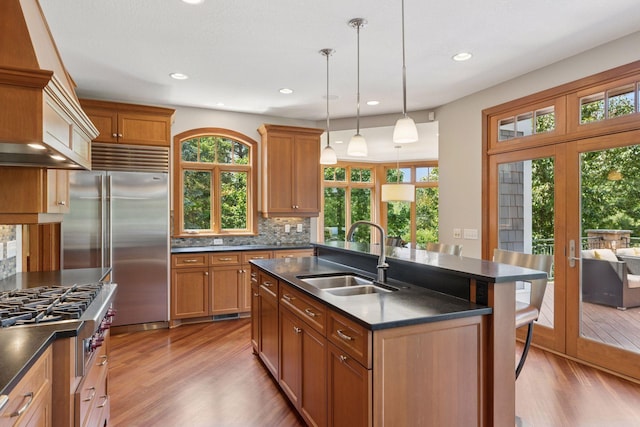 9726 Whistling Valley Rd, Lake Elmo, MN 55042 - kitchen with a sink, stainless steel appliances, dark countertops, light wood-style floors, and recessed lighting