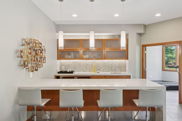 9726 Whistling Valley Rd, Lake Elmo, MN 55042 - kitchen with a sink, a kitchen bar, decorative backsplash, glass insert cabinets, and recessed lighting
